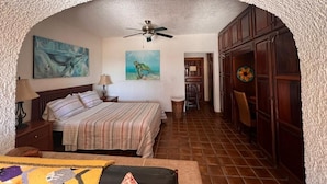 Un dormitorio con una cama, ventilador de techo y obras de arte en las paredes.