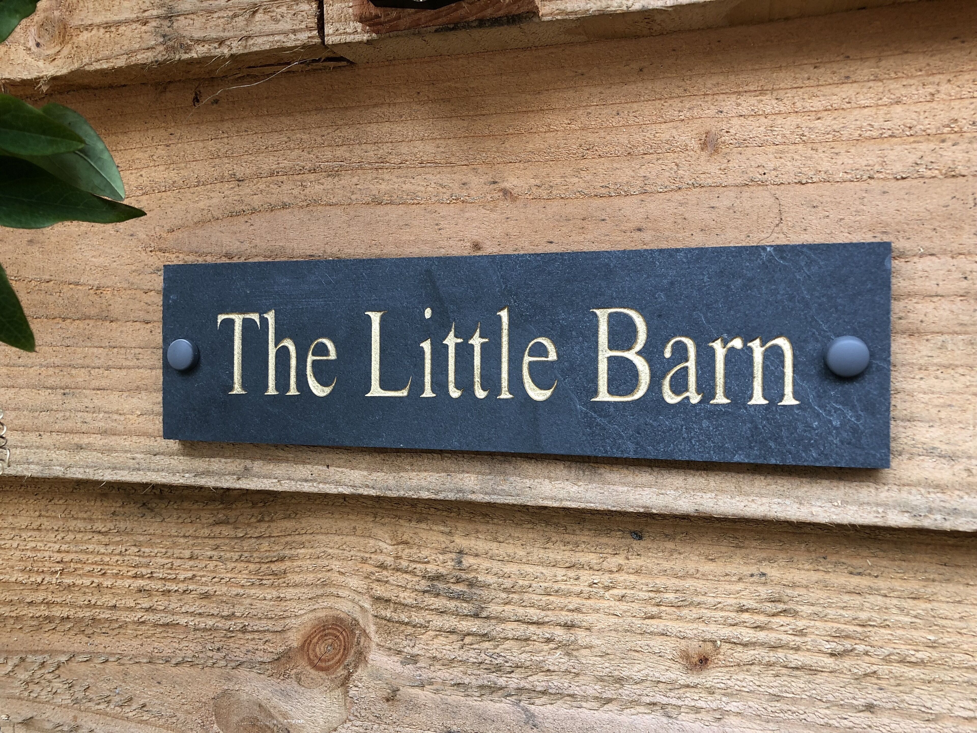 Un letrero que dice 'The Little Barn' colocado sobre una superficie de madera.