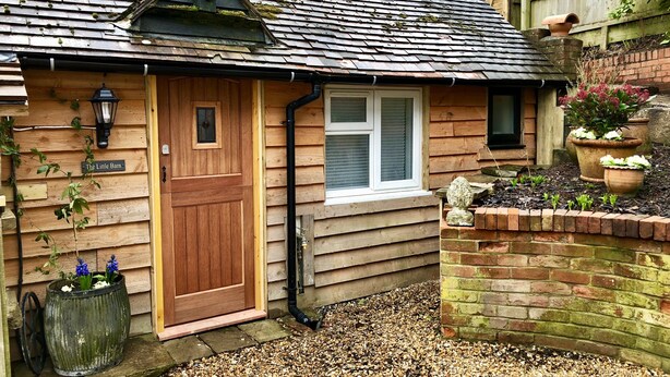 A wooden house with a sloped roof, a front door, a window, and a small porch area with a potted plant. - Perfect for walkers, Goodwood, National Trust, Short Stay (Bramshott Chase)