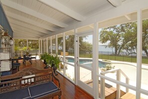 Relax in a spacious room with a high ceiling, large windows offering a view of the outdoor pool and lush surroundings.