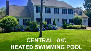 A two-story house with a well-maintained lawn and a swimming pool.