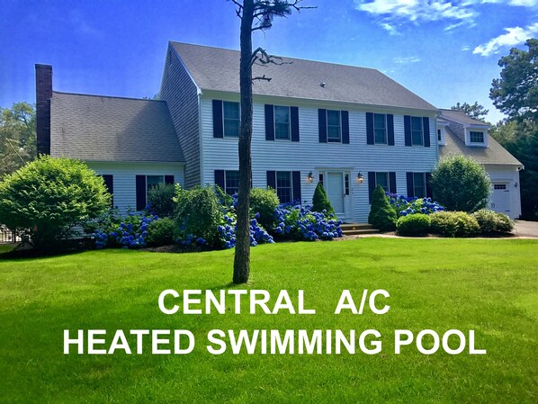 A two-story house with a well-maintained lawn and a swimming pool.