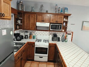 A kitchen with wooden cabinets, a microwave, a stove, and various kitchen appliances.