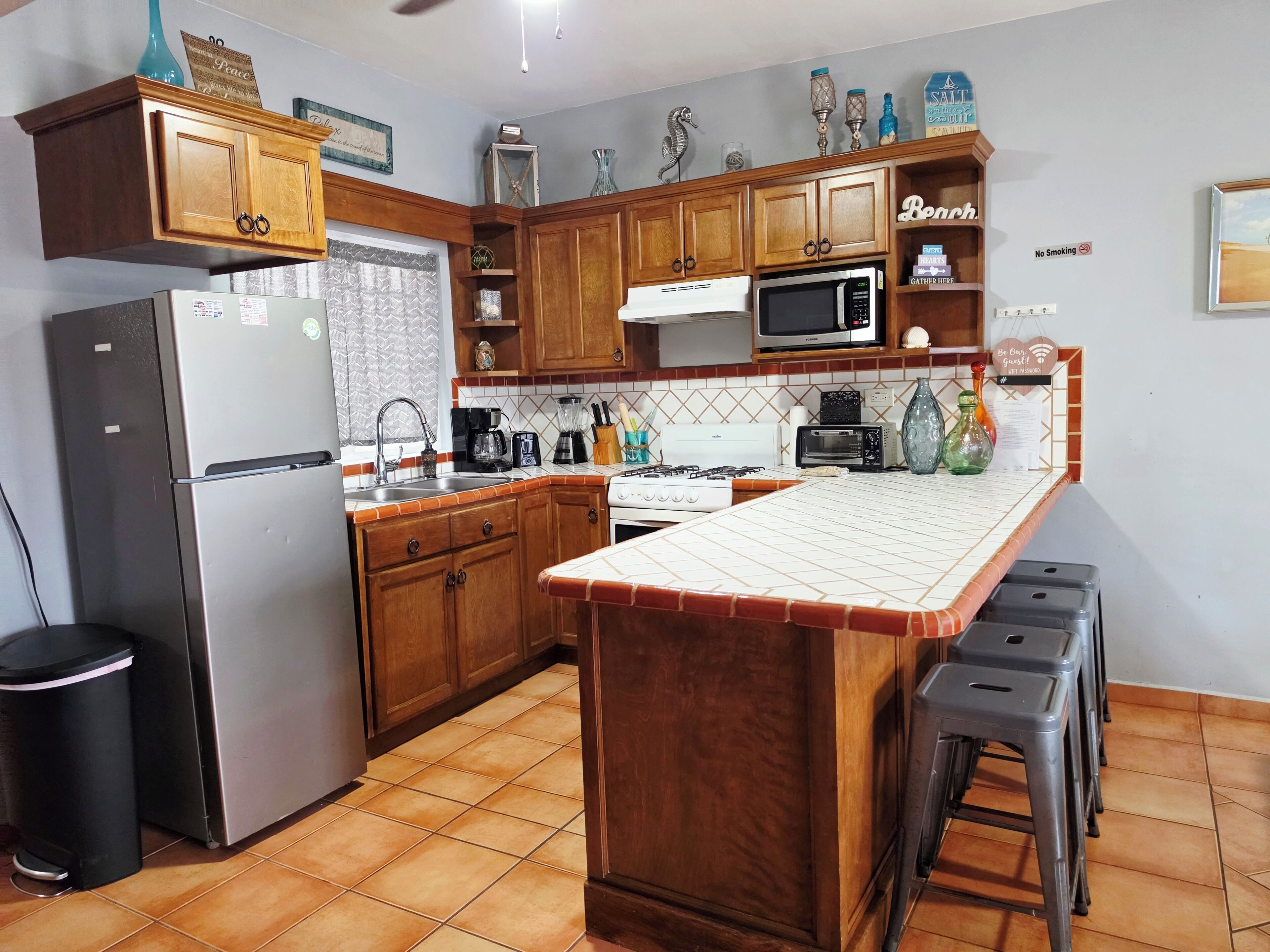 Una cocina con armarios de madera, un refrigerador, un microondas, una estufa y un salpicadero de azulejos.