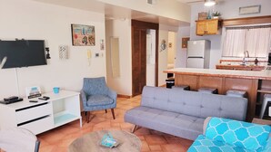 Een woonkamer met een bank, fauteuil, televisie en een bijzettafeltje.