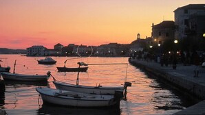 A harbor at sunset with boats docked, a waterfront promenade, and buildings in the background. - Waterfront Dalmatian Stone Villa with Panoramic Adriatic Views, Kastel Novi (Kaštel Novi)