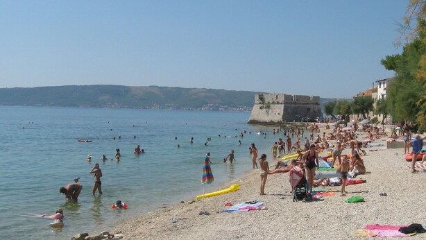 A crowded beach with people swimming and sunbathing, a castle in the background, and a clear sky. - Waterfront Dalmatian Stone Villa with Panoramic Adriatic Views, Kastel Novi (Kaštel Novi)