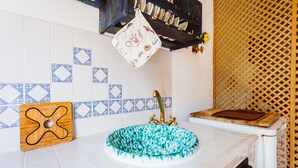 Een badkamer met een wastafel met blauw-wit patroon, een houten snijplank en een decoratieve tegelachtergrond.