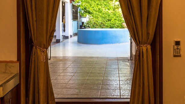 Un vano con cortinas, una pared azul y un suelo de baldosas.