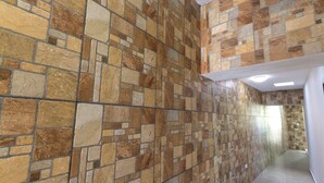 Un pasillo con un muro de mosaico de piedra y suelo de baldosas.