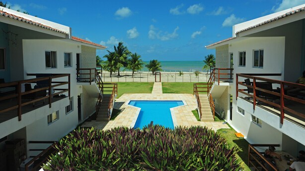 Ein Resort mit Pool, Palmen und Blick auf den Ozean.