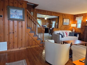 Un intérieur en bois avec un escalier, un canapé blanc et une table à manger.
