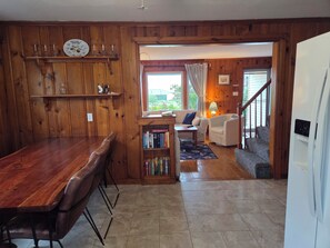 Un intérieur en bois comprenant une table à manger, des étagères, un canapé et un escalier menant à un espace extérieur.