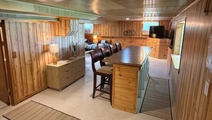A spacious kitchen with wooden cabinetry, a central island, and a dining area with chairs. - Beautiful lakefront, family-friendly! (Hustisford)