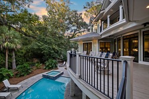 A pool with a deck, surrounded by lush greenery and trees.
