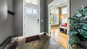 A hallway with a white door, a potted plant, and a bench.
