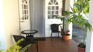 A covered patio with a table and two chairs, a potted plant, and a door with glass panels. - Rodney Bay Beach Home near EVERYTHING (Rodney Bay)