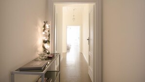 A hallway with a glass table displaying a book and a decorative item. - Central 7 pax apartament Near The Colosseum! (rome)