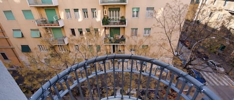 A multi-story residential building with balconies, a central courtyard, and a metal railing.