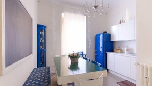 A compact kitchen with a dining table, chairs, a blue cabinet, and a refrigerator. - Central 7 pax apartament Near The Colosseum! (rome)