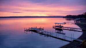 Un lago tranquilo al atardecer con muelles y un pequeño edificio.