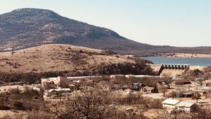 Un pueblo con una colina destacada y una presa al fondo.
