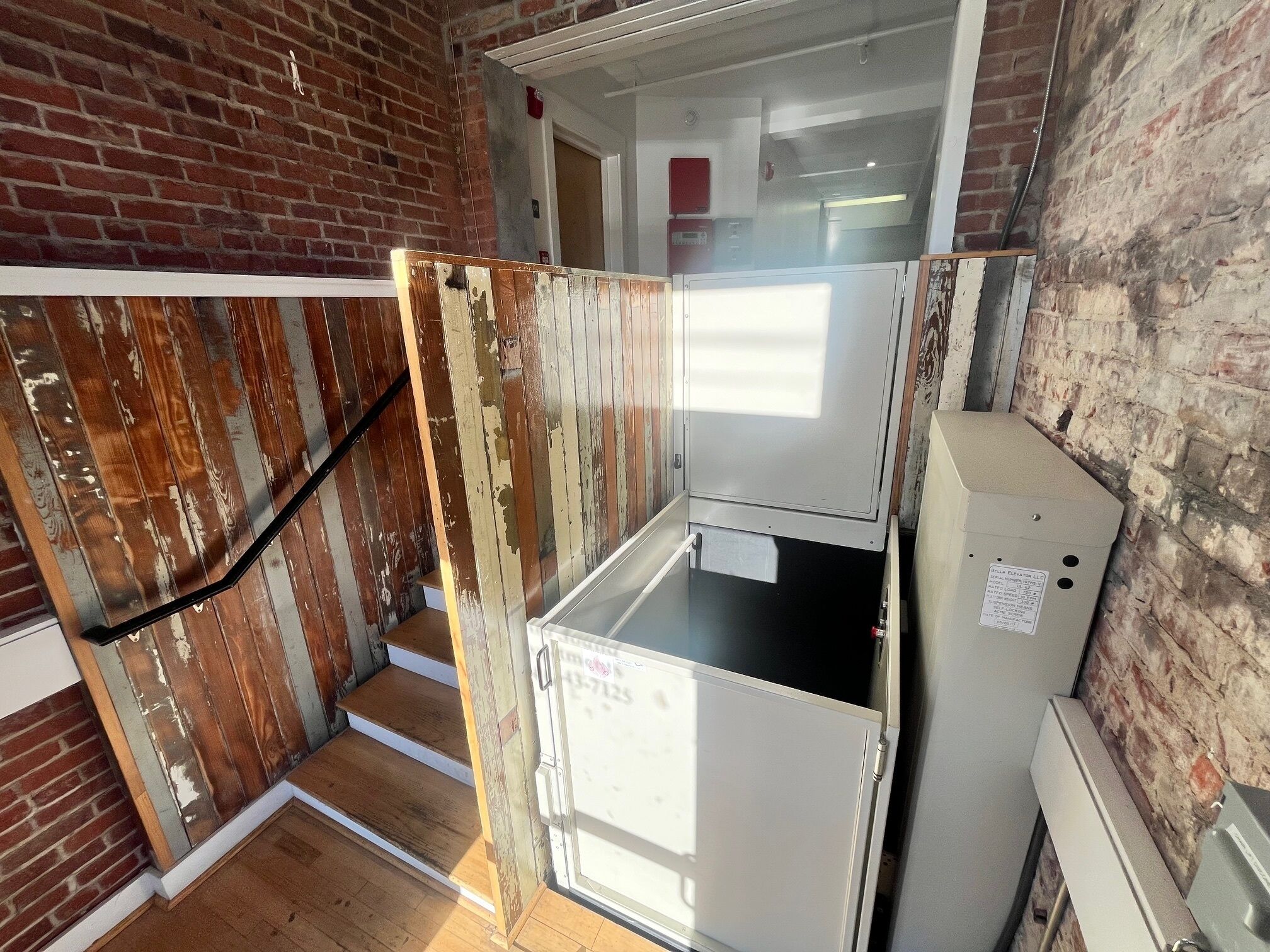 Une cuisine équipée d’un réfrigérateur, d’un escalier en bois et d’un mur en briques.