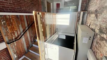 Une cuisine équipée d’un réfrigérateur, d’un escalier en bois et d’un mur en briques.