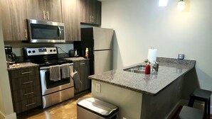 A modern kitchen with stainless steel appliances, a granite countertop, and a small island with a sink.