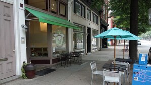 A storefront with outdoor seating, a green awning, and a sign with a winged logo.