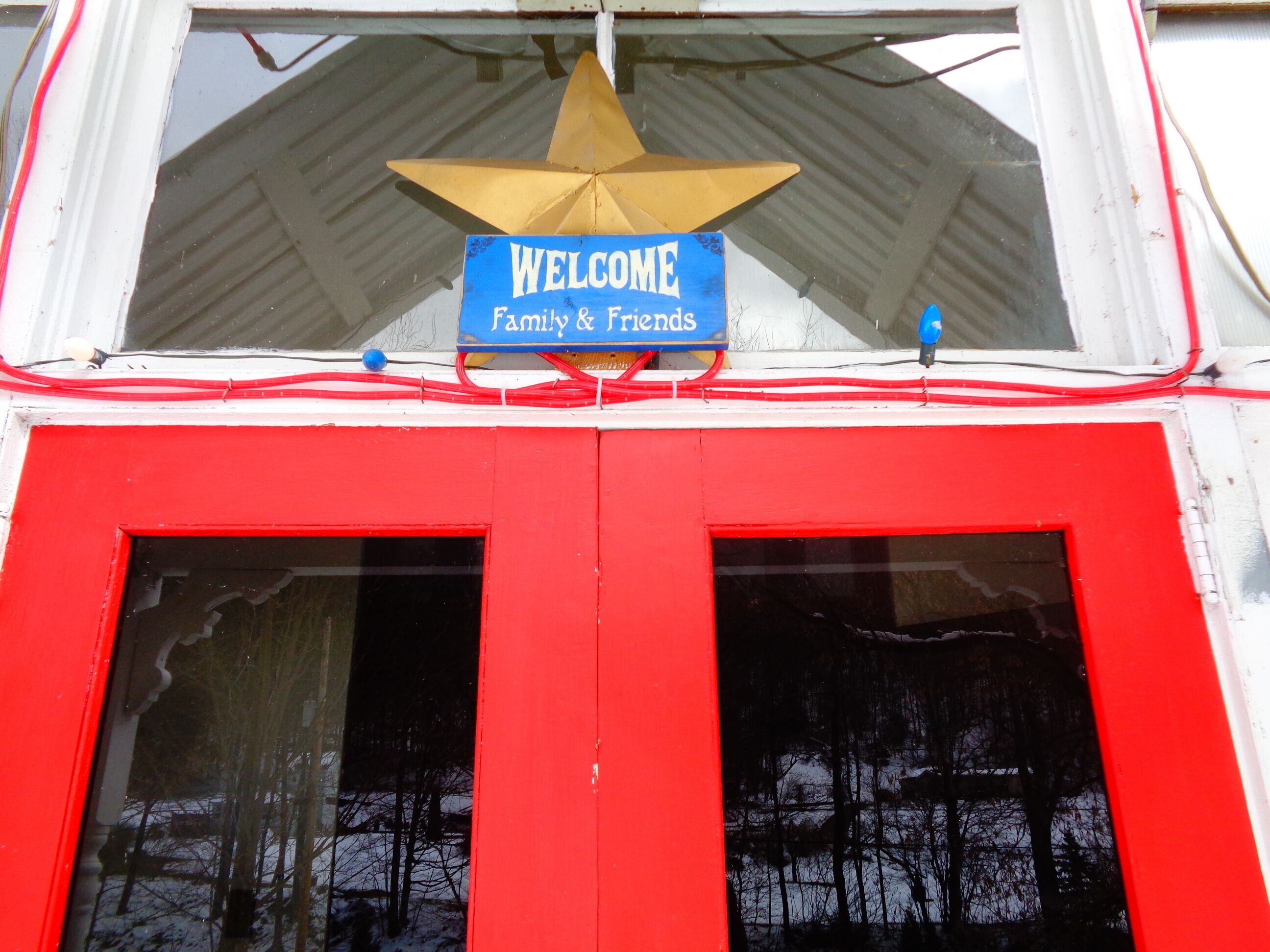 Un edificio rojo y blanco con un cartel que dice 'WELCOME Family & Friends' sobre un ventanal grande.