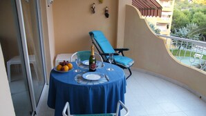 A balcony with a table set for two, featuring a blue tablecloth, a bottle of champagne, and a plate of fruit. - Front Line Apartment south facing with Pool, next to Sea, new fibre internet. (El Campello)