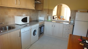 A kitchen with a washing machine, microwave, oven, and a sink. - Front Line Apartment south facing with Pool, next to Sea, new fibre internet. (El Campello)