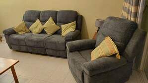 A living room with two grey sofas, one with yellow cushions and one with a striped cushion. - Front Line Apartment south facing with Pool, next to Sea, new fibre internet. (El Campello)