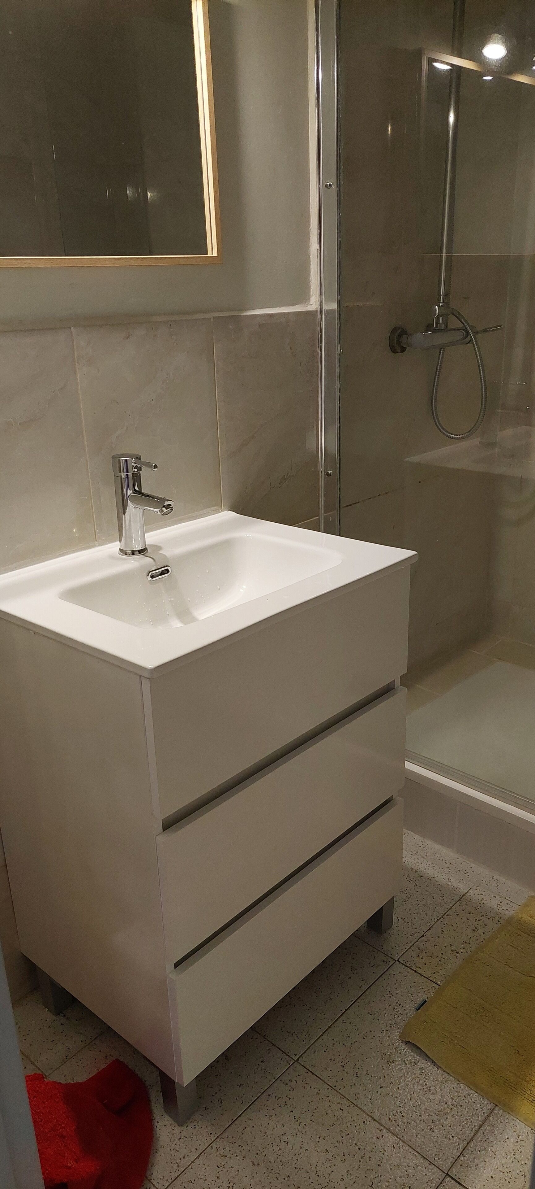 Ein Badezimmer mit einem weißen Waschbecken, einem Spiegel und einer Dusche.