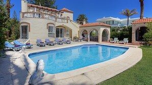 A pool area with lounge chairs and a statue.