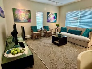 A living room with a sofa, two chairs, a coffee table, and artwork on the walls.
