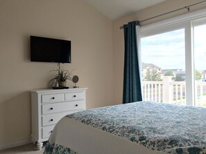Relax in this serene bedroom with a large bed and flat-screen TV, featuring a beautiful view of the surrounding area.