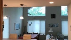 Ein Essbereich mit Holztisch und Stühlen, einer Couch und einem Mülleimer.