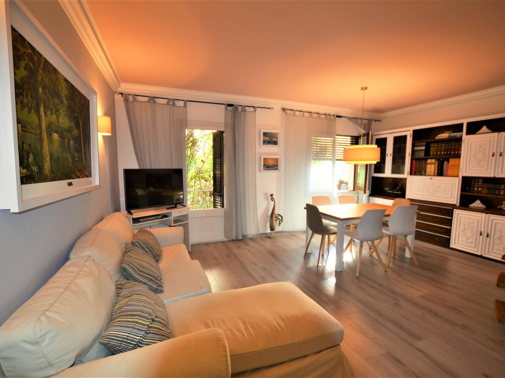 A living room with a sofa, TV, dining table, chairs, and a bookshelf.