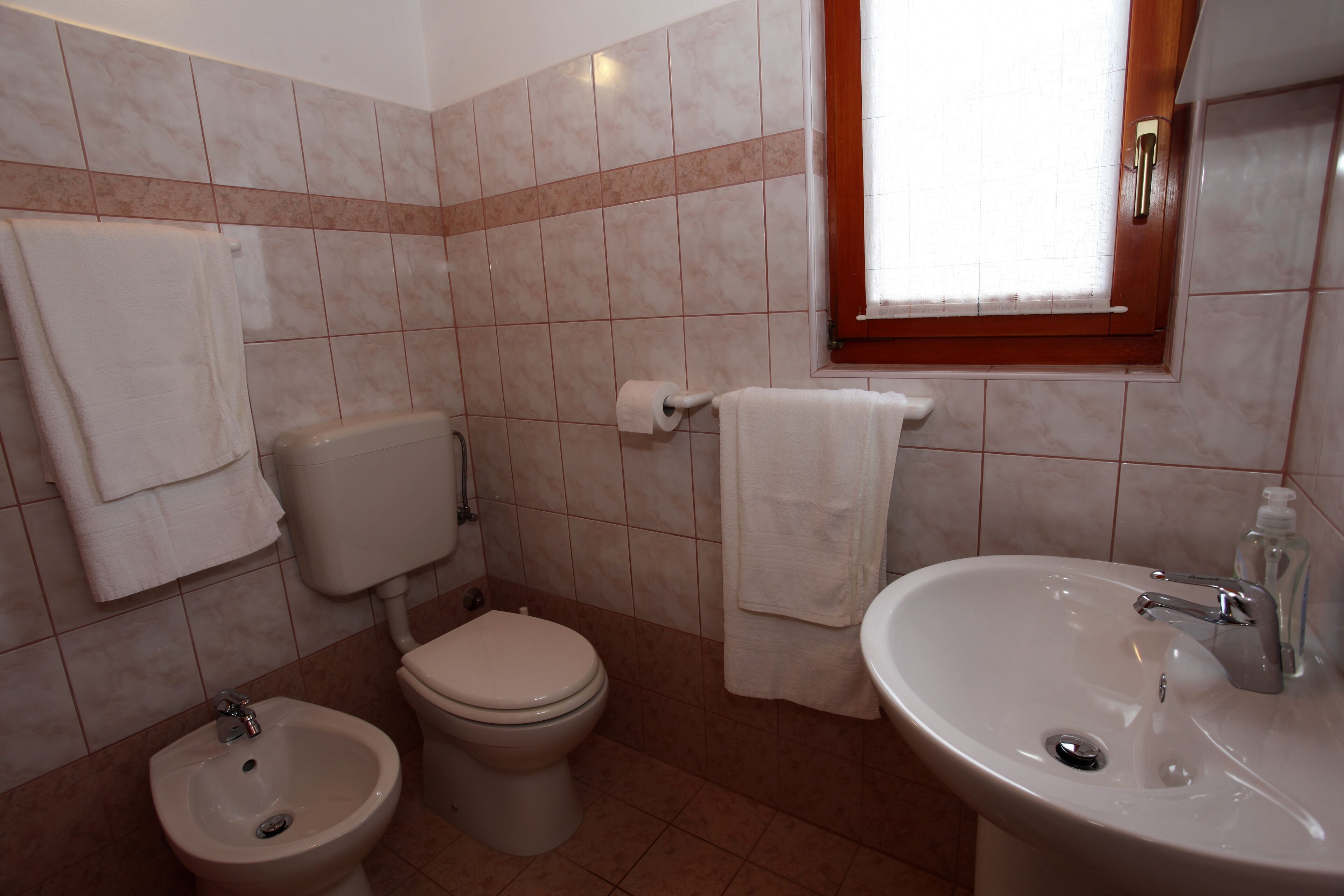 Une salle de bain équipée de toilettes, d’un bidet, d’un lavabo et de serviettes.