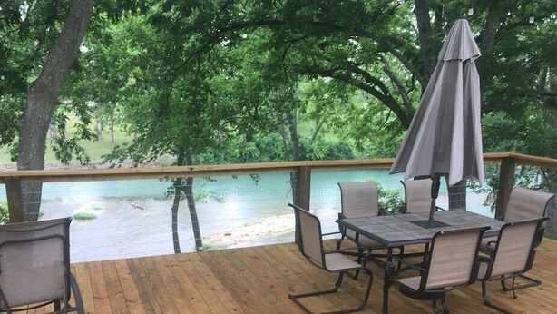 Terraza al aire libre con mesa y sillas, con vista a un cuerpo de agua.