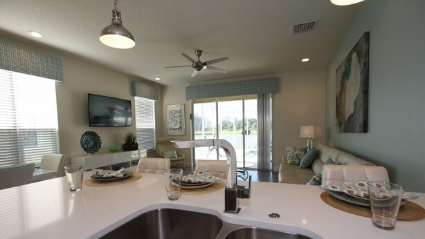 A modern kitchen with a central island, double sinks, and a ceiling fan. - Outstanding, owner operated Townhome,  even a TV in the pool area! (Clermont)