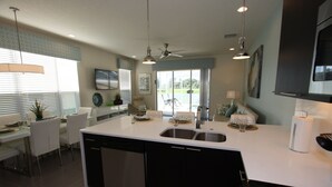 A modern kitchen with a large island, built-in dishwasher, and a dining area with a table and chairs. - Outstanding, owner operated Townhome,  even a TV in the pool area! (Clermont)