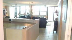 A spacious living area with a kitchen island, large windows, and a seating area with a couch. - Awesome 6th Story View Of The Ocean, Pool And Beach  (Ponce Inlet)