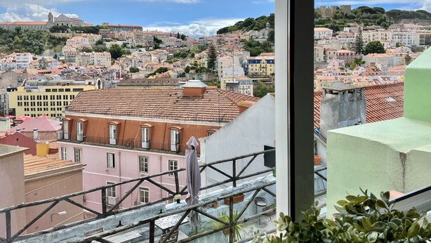 Une vue sur une ville, avec des bâtiments, un pont et un château qui se dessinent à l'horizon.