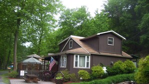 A two-story house with a porch, a picnic table, and an American flag.