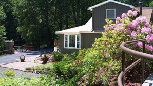 A house with a sloped roof, surrounded by lush greenery and flowering plants.