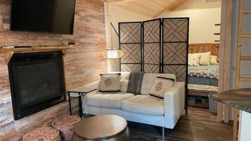 A modern living room with a flat-screen TV, a white sofa, a coffee table, and a decorative partition.