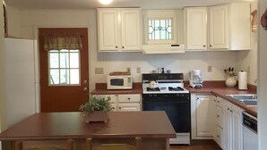 A kitchen with white cabinets, a wooden table, and chairs.